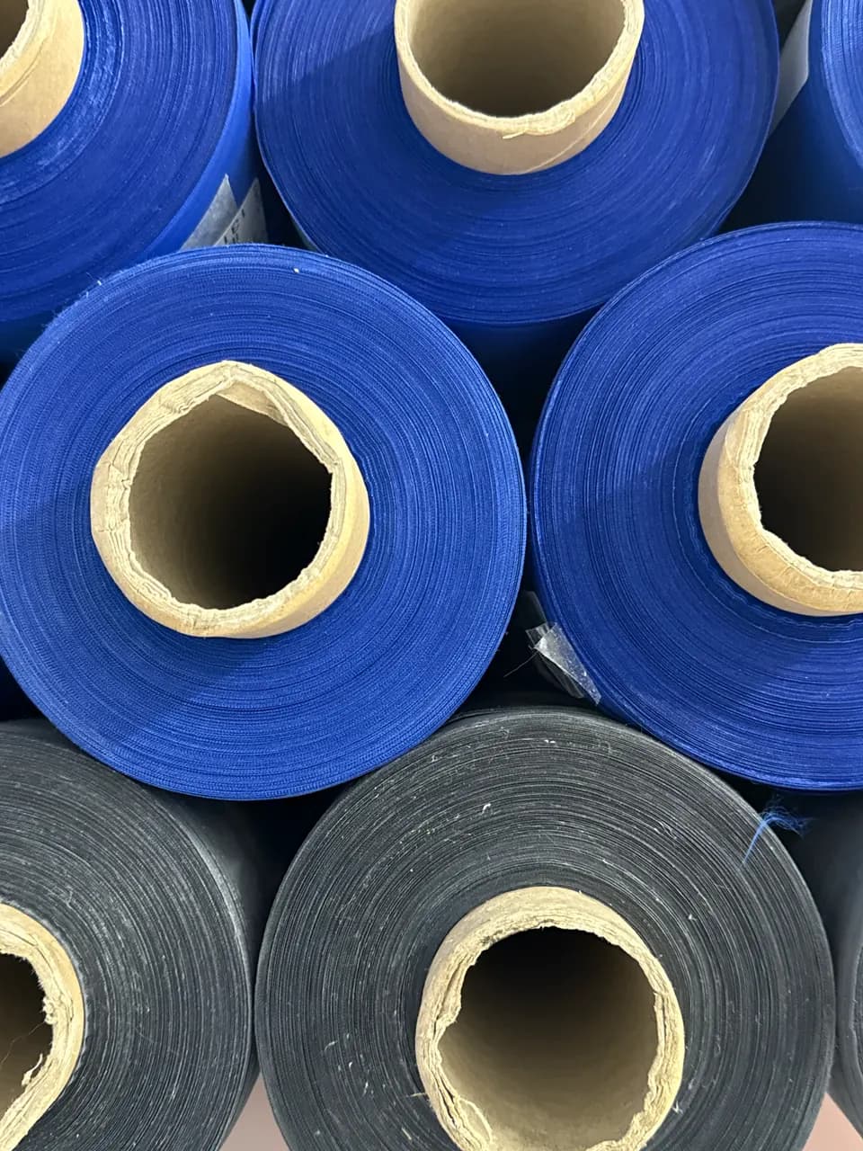 Fabric rolls in shades of blue and charcoal.