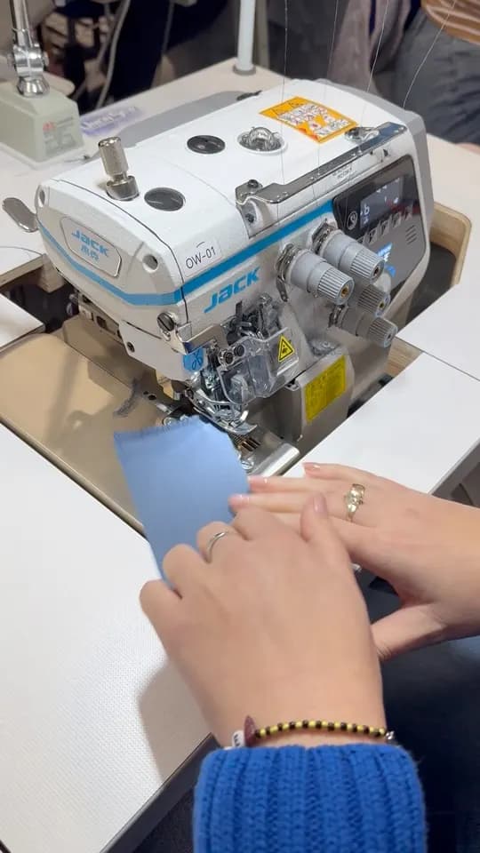 Blue fabric being sewn on an overlocker.